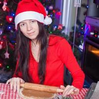 Young woman in Christmas hat baking gingerbread at home photo