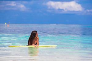 Young surfer woman surfing during beach vacation photo