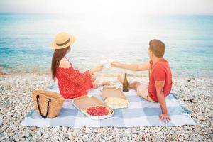 encantadora pareja joven haciendo un picnic en la playa foto