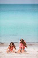 Little happy funny girls have a lot of fun at tropical beach playing together. photo