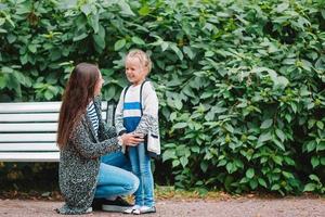 Little girl with mom outdoors in park at autumn day photo