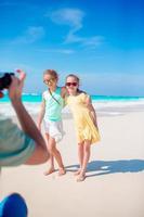 Father take photo of his little girls on white tropical beach on caribbean island have a lot of fun