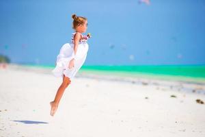 adorable niña en la playa durante las vacaciones de verano. lindo niño divirtiéndose saltando y disfrutando de sus vacaciones en la playa foto