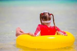 Adorable little girl with inflatable rubber circle during beach vacation. Kid having fun on summer active vacation photo