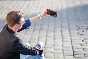 Close up of male hands is holding cellphone outdoors on the street. Man using mobile smartphone. photo