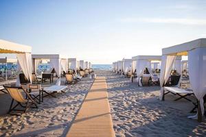 tumbonas de madera frente a un mar turquesa a la luz del atardecer. tumbonas en la famosa playa de arena italiana en forte dei marmi foto