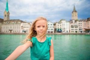 Adorable little girl taking selfie outdoors in Zurich, Switzerland. Closeup portrait of kid background of beautiful city photo