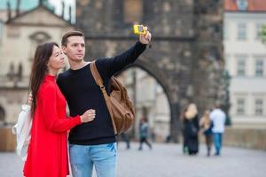 Young couple traveling on holidays in Europe smiling happy. Caucasian family making selfie in popular Karlov Most photo