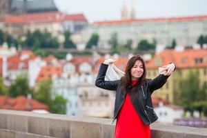 Happy young urban woman in european city on the famous bridge. Caucasian tourist walking in Prague, Czech Republic photo