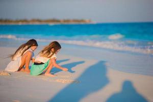 adorables niños divirtiéndose juntos dibujando en la arena de la playa blanca foto