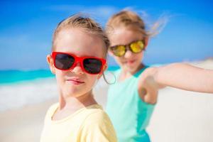 Cute little girls taking selfie at tropical beach on exotic island during summer vacation photo