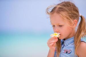 retrato de una niña adorable con flores en las vacaciones de verano en la playa foto