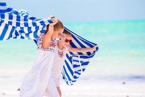 Little girls having fun running with towels on tropical beach. Kids enjoy their family summer vacation in the Indian Ocean photo