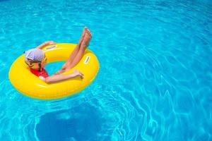 Little girl with inflatable rubber circle having fun in swimming pool photo