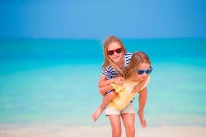 adorables niñas caucásicas en la playa durante las vacaciones de verano. niños felices divirtiéndose juntos en sus vacaciones familiares de verano. foto