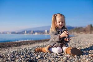 Adorable little girl on the beach having fun at warm winter day photo