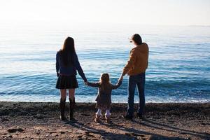 padres jóvenes con su pequeña hija cerca del mar negro foto