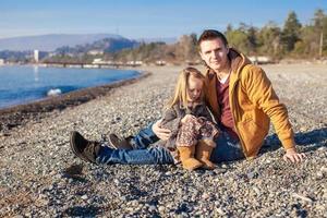 joven padre y su pequeña hija en la playa en un soleado día de invierno foto