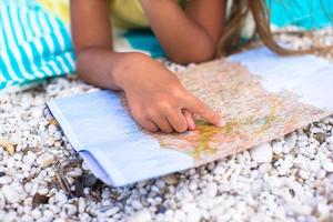 adorable niñita con un gran mapa en vacaciones en la playa tropical foto