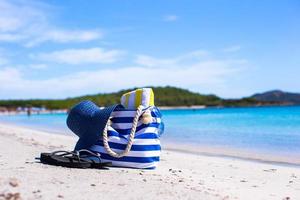 Straw hat, bag, sunglasses and towel on white tropical beach photo