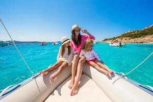 Young mother with her adorable little girls resting on a big boat photo