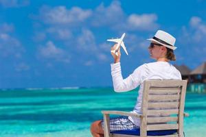 Young man with miniature of an airplane at tropical beach photo