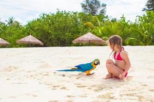 Adorable little girl at beach with colorful parrot photo