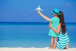 mujer joven y niña con miniatura de avión en la playa foto