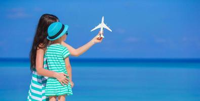 Young woman and little girl with miniature of airplane at beach photo