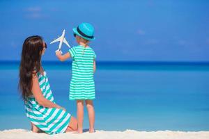 Young woman and little girl with miniature of airplane at beach photo
