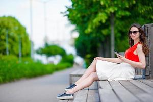 Beautiful girl listening music by smartphone on summer holidays. Young attractive tourist with mobile phone outdoors enjoying holidays. photo