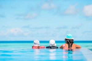 madre y dos hijos disfrutando de las vacaciones de verano en una piscina de lujo foto