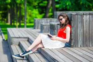 Beautiful girl listening music by smartphone on summer holidays. Young attractive tourist with mobile phone outdoors enjoying holidays. photo