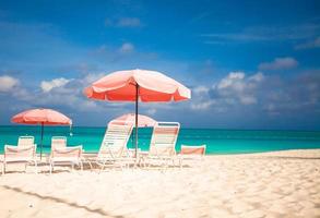 Paradise view of tropical empty sandy plage with umbrella and beach chair photo