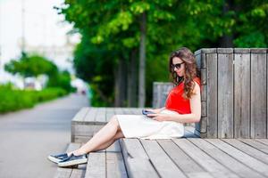 Beautiful girl listening music by smartphone on summer holidays. Young attractive tourist with mobile phone outdoors enjoying holidays. photo