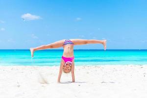 Active little girl at beach having a lot of fun on summer vacation. Adorable kid jumping on the seashore photo