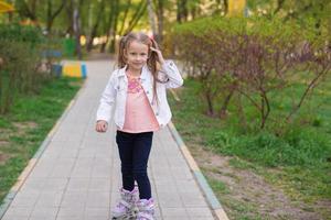 Adorable little girl on roller skates in the park photo