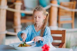 Adorable little girl having dinner at outdoor cafe photo