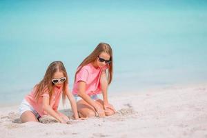 Two kids making sand castle and having fun at tropical beach photo