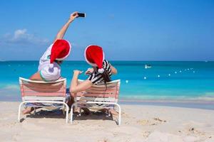 Young happy couple in red Santa hats taking a photo