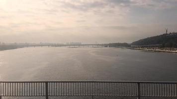 bridge over the Dnieper in Kiev. Metro train rides on the bridge. View from the bridge to the Dnieper River in the early morning at dawn, the camera moves along the bridge over the river. video