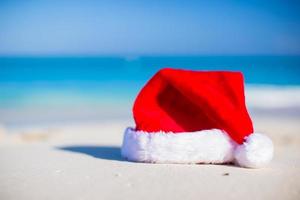 Closeup christmas hat on a white sandy beach photo