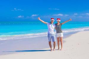 Young happy couple in red Santa hats enjoy summer vacation photo