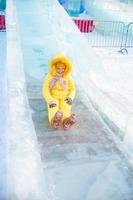 Adorable little girl riding on an ice hill outdoors photo
