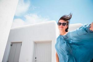 joven hermosa mujer tomando selfie con teléfono al aire libre casa blanca de fondo foto