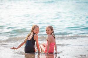 Little happy funny girls have a lot of fun at tropical beach playing together. photo