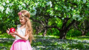 Happy little adorable girl in blossoming apple tree garden photo