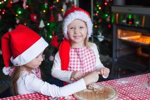 Niñas horneando galletas de jengibre para Navidad con gorro de Papá Noel foto