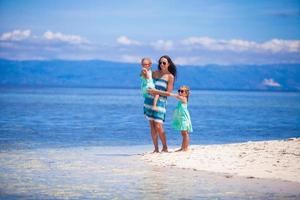 adorables niñas y madre joven en una playa blanca tropical en una isla desierta foto