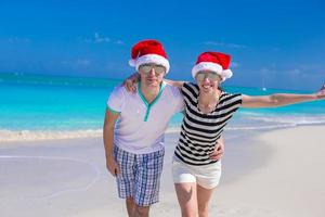 Portrait of young couple in Santa hats enjoy beach vacation photo